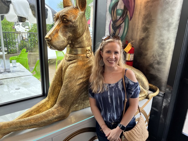 Girl About Dayton with a giant dog statue at Agave & Rye Centerville