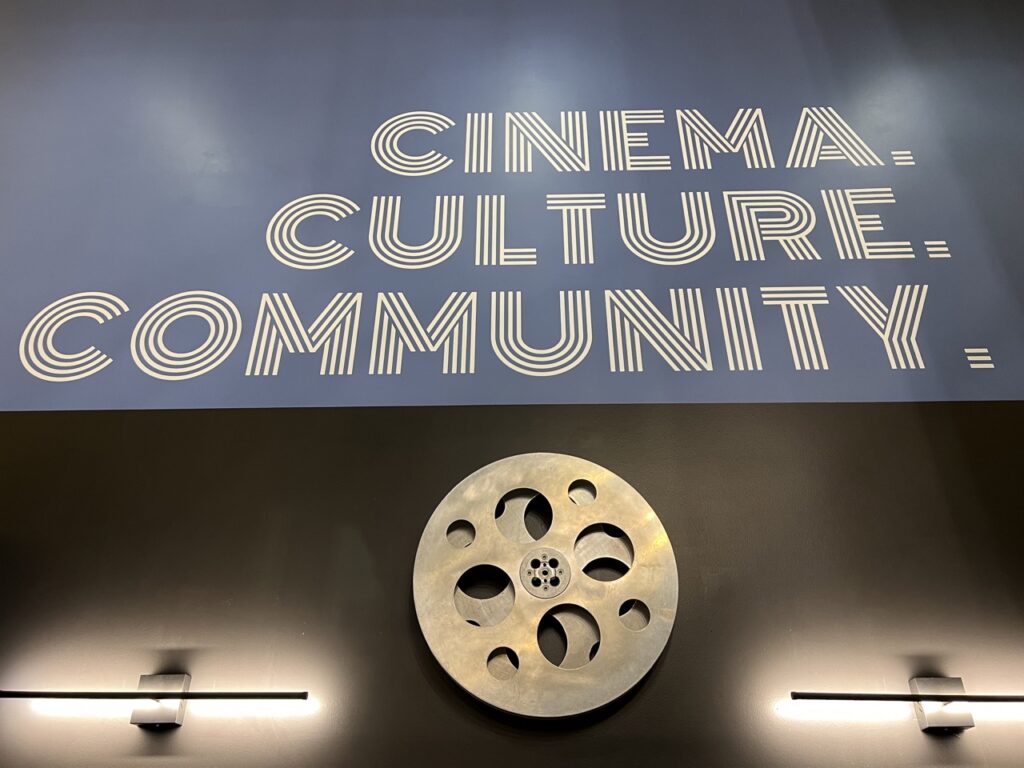 Neon theatre sign stating cinema, culture, community